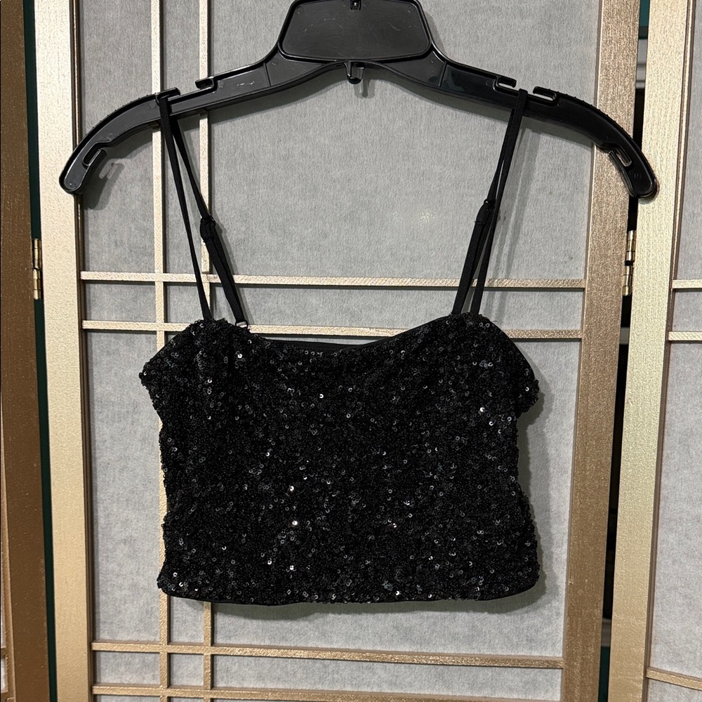 black sequined camisole top with adjustable spaghetti straps & a cropped fit.